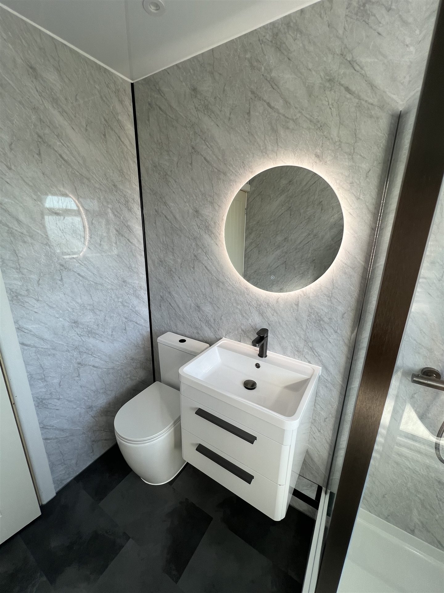 Close view of marble-effect bathroom vanity with backlit mirror
