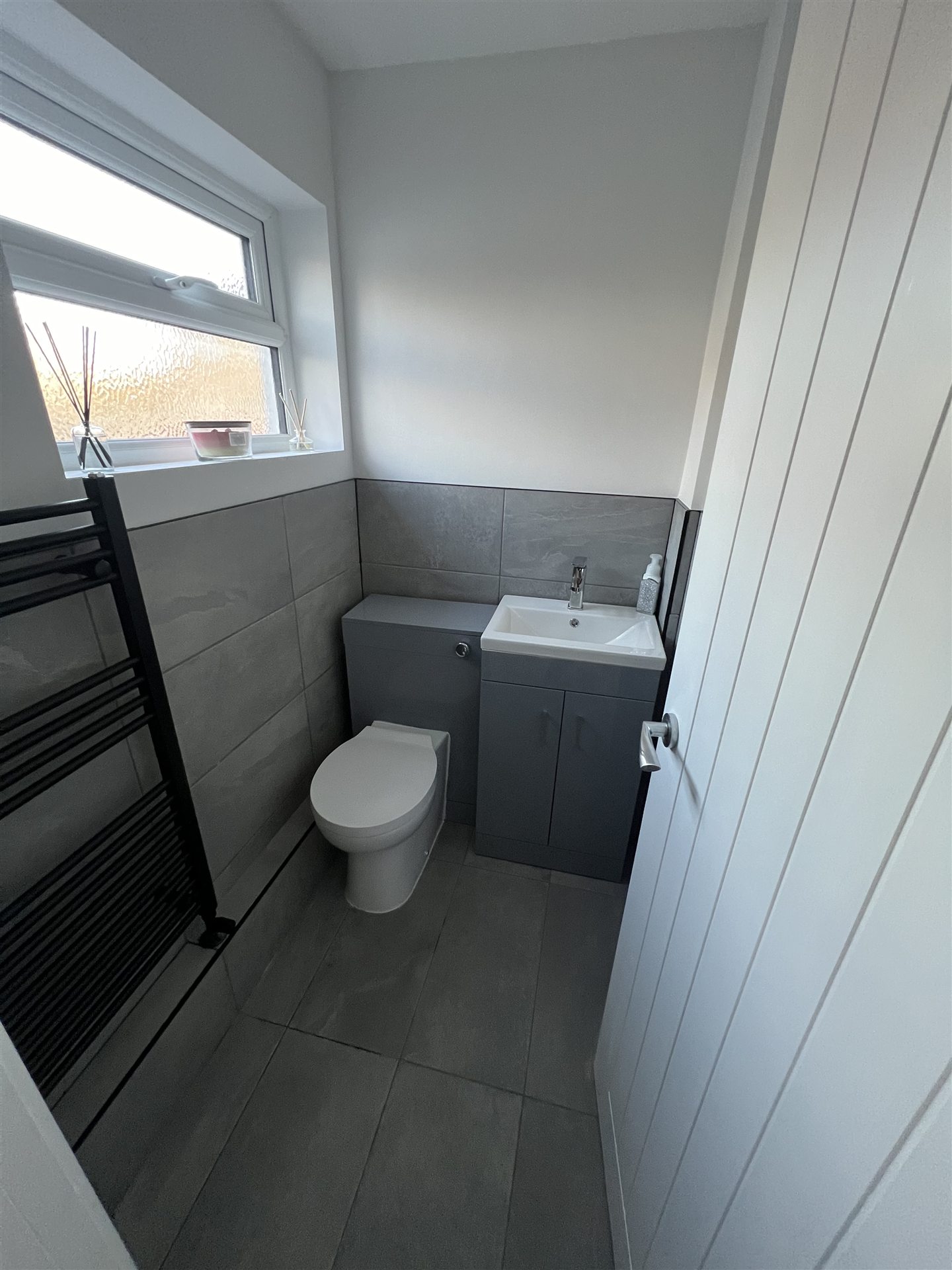 Modern grey tile bathroom, black towel radiator and grey vanity unit