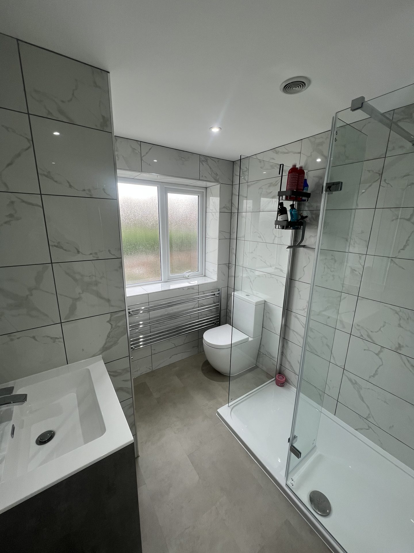 White marble-effect bathroom with corner glass shower, renovated by KPR Plumbing & Heating