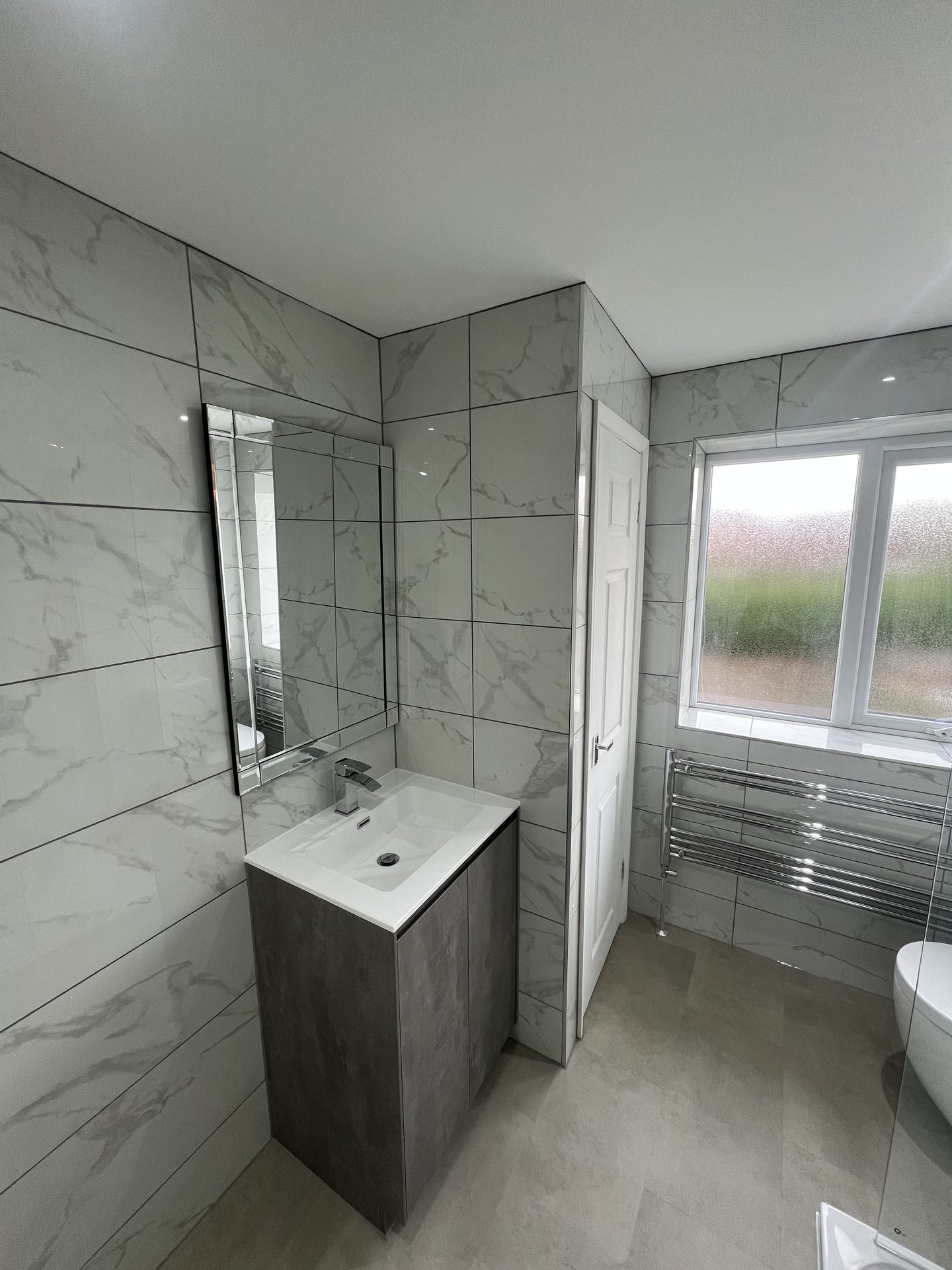 Bathroom vanity nook with mirrored cabinet and chrome heated towel rail