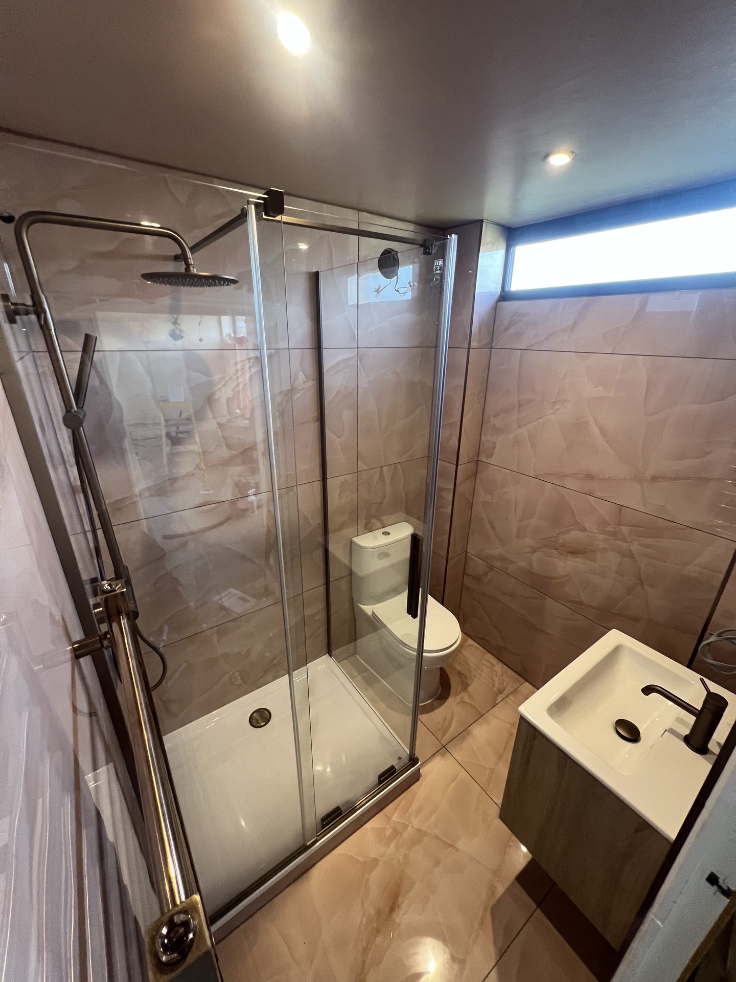 Stone-effect bathroom with black fittings and frameless glass shower door