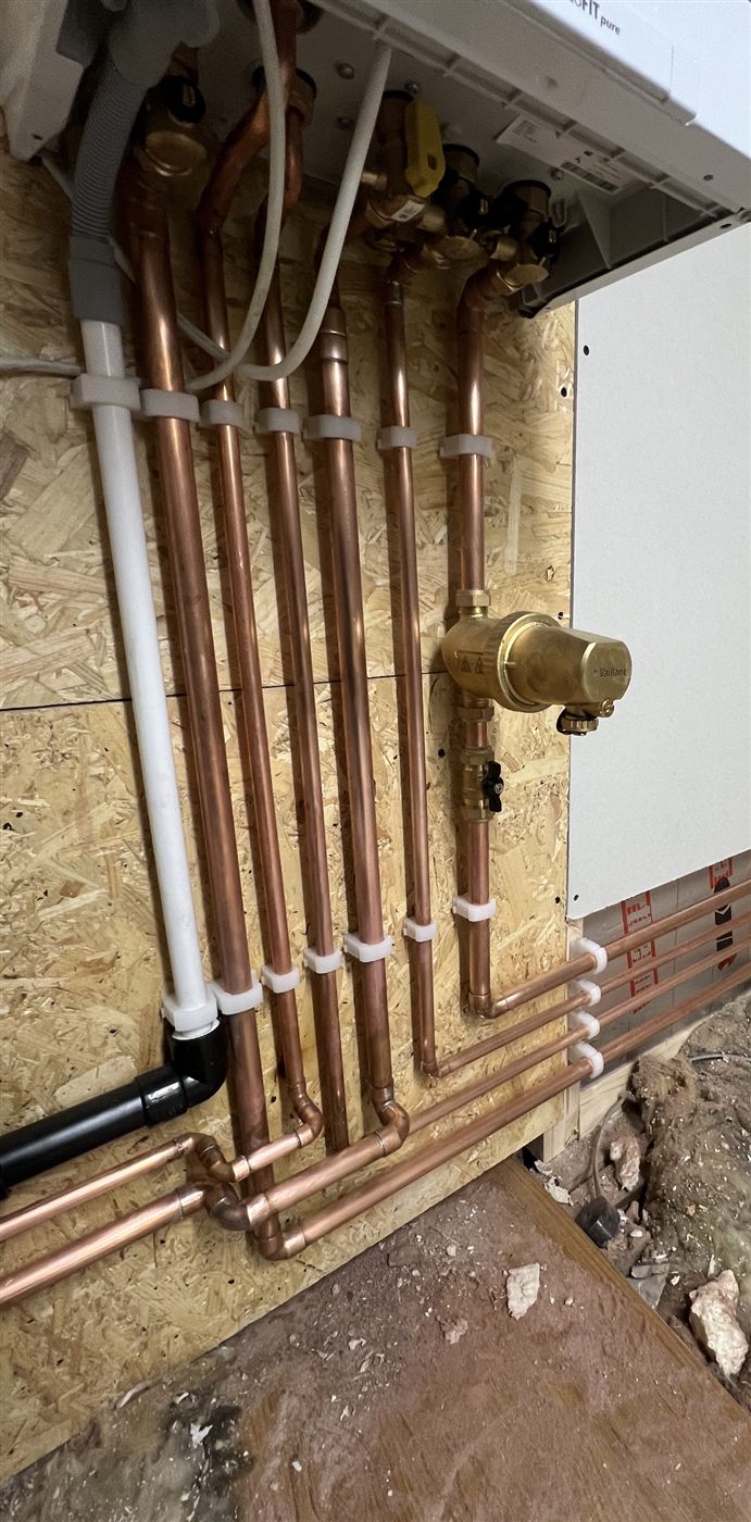 Close-up of neatly clipped copper pipework beneath a newly installed boiler