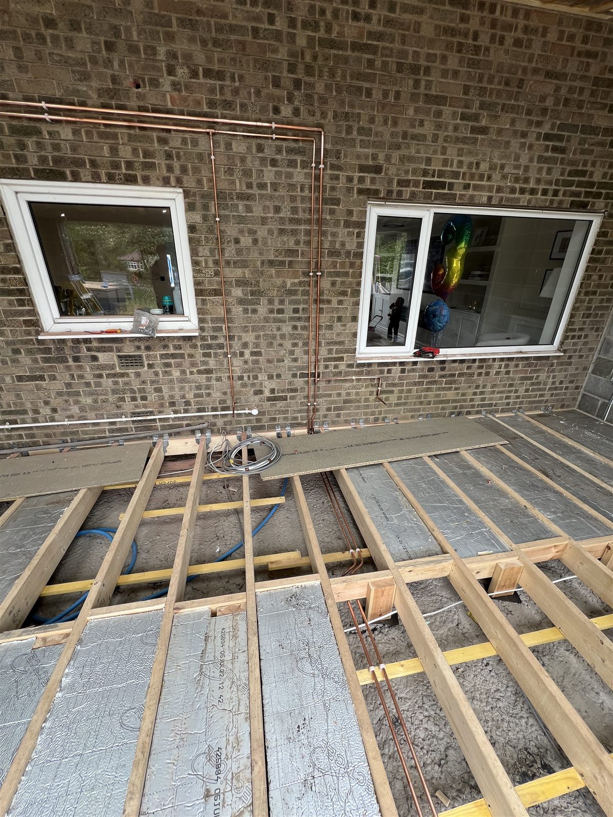 Exterior copper pipe run installed neatly along a brick wall for a house extension