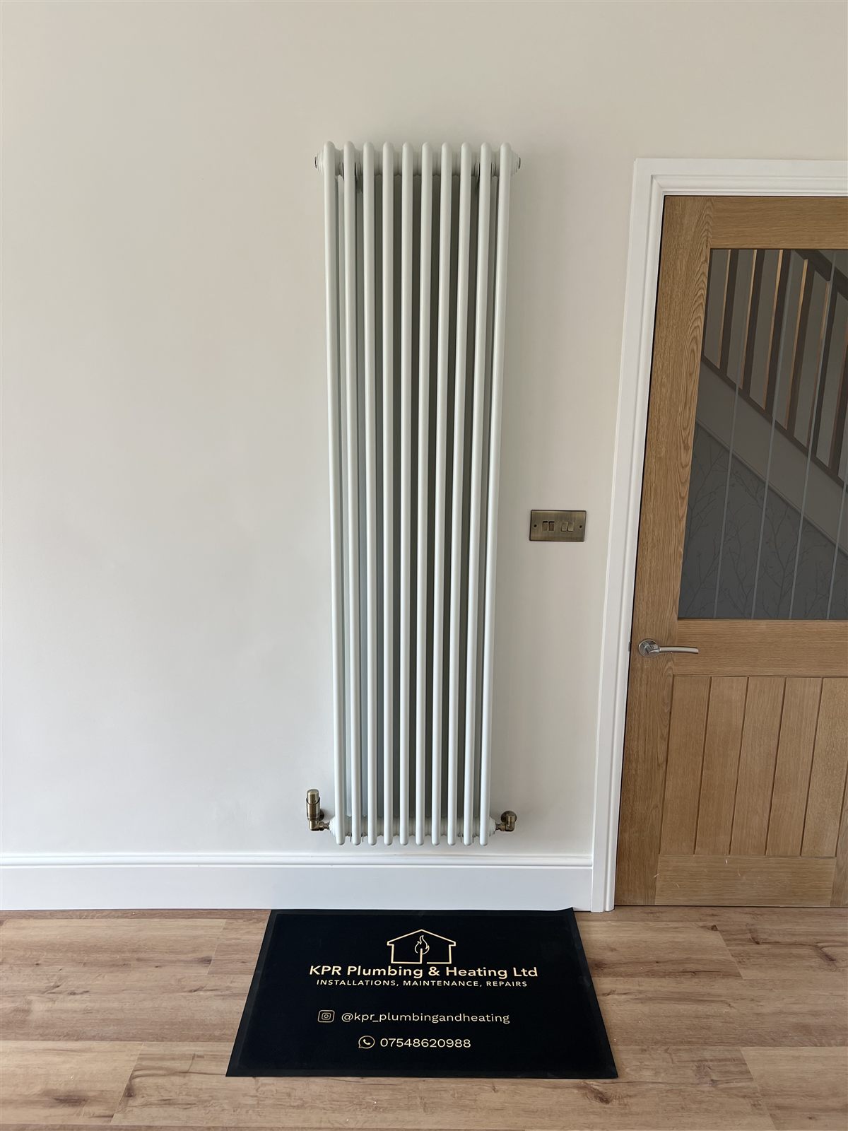 Column radiator installation with polished brass valves and copper pipework