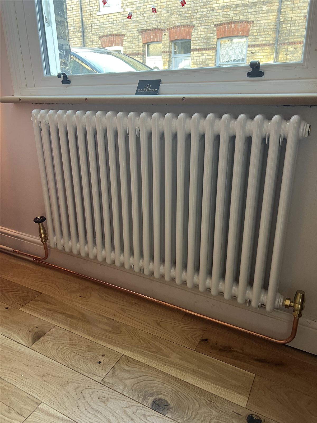 Column radiator installation with exposed copper pipework and brass valves